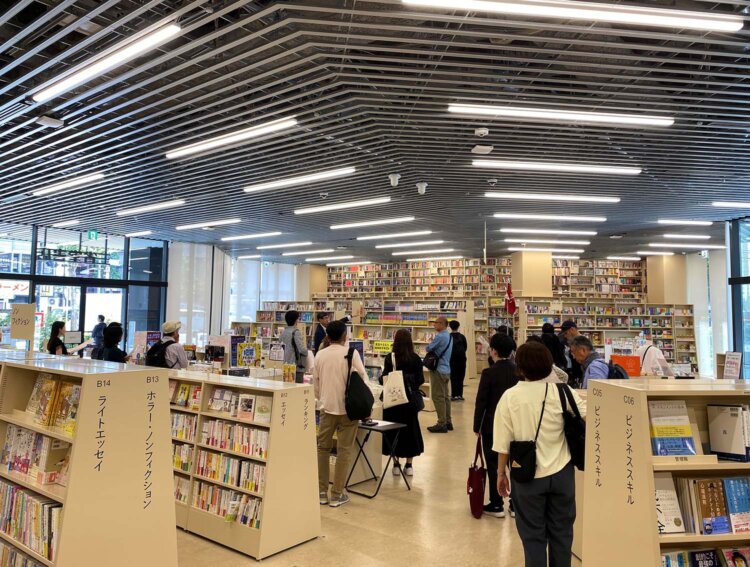 新店舗のテーマは「歩けば、世界がひろがる書店。」。目的の本を探していると、新たな興味が湧いてくる仕掛けが随所にちりばめられています。参加者の多くが、「世界の展望台」と名付けられた少し高くなっている場所（写真奥）から店内を見渡していました。