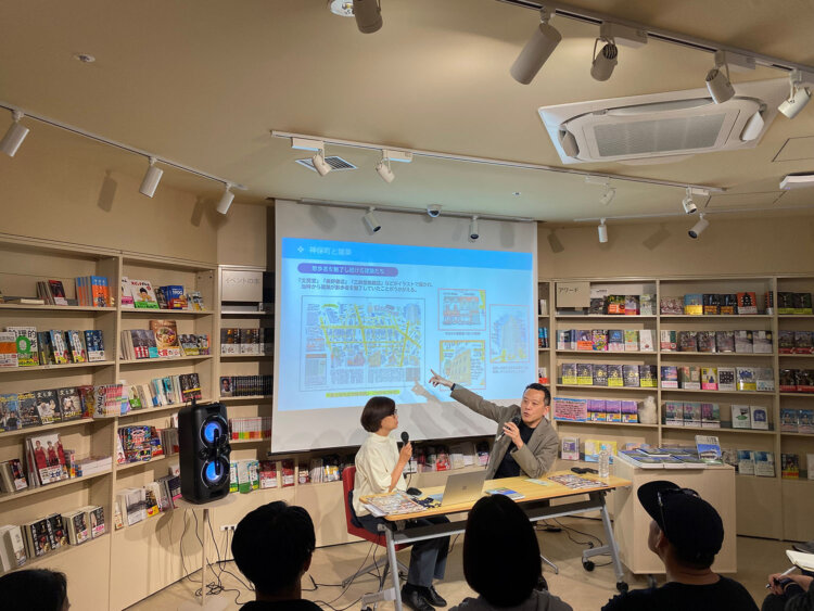 神保町のイラストマップを指し示しながら話す倉方さん（右）。建築史家目線の解説で、街の造りがどうしてそうなっているのかが見えてきます。