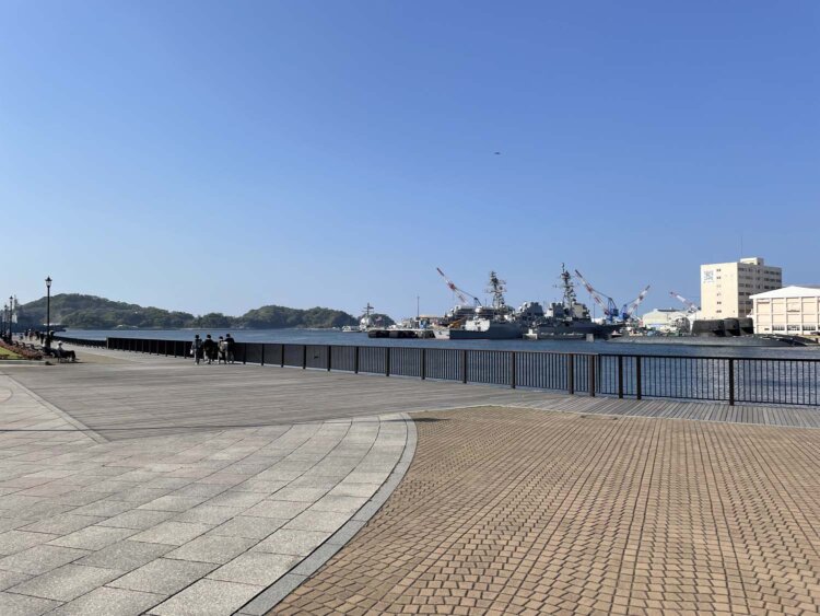 ボードウォークを歩く子供たちと、その向こうに見える艦船と潜水艦。