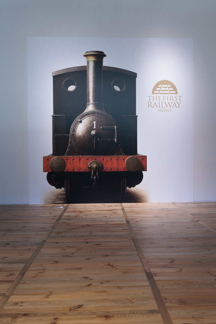 『TAKANAWA GATEWAY CITY』内にあるギャラリーの床材には、遺構から掘り出された松が再利用されている。写真の一号機関車は実物大で、線路の幅は現在も変わっていない。
