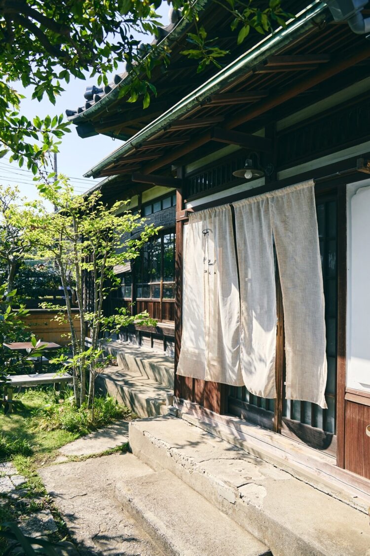 庭の緑と白いのれんで涼しげな玄関。