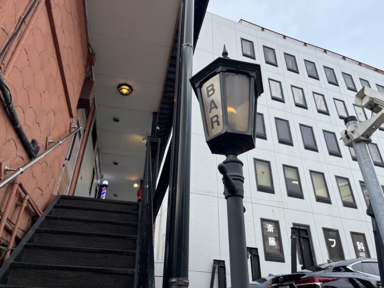 ガス灯のようなランプのたもとに店へとつながる階段がある。