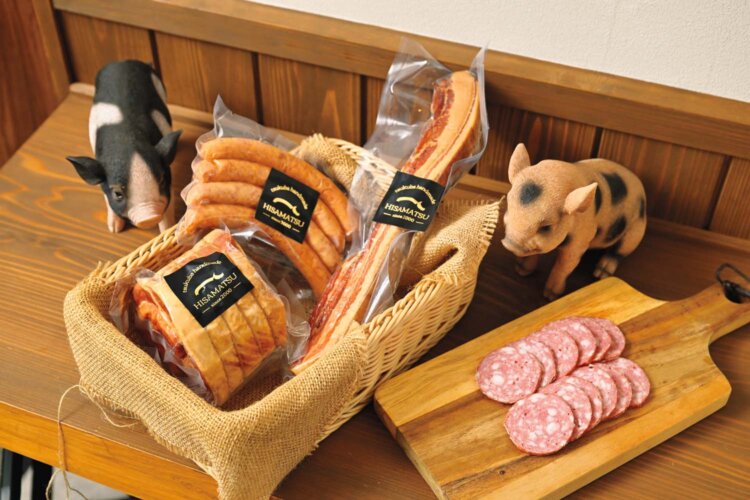 左上から時計回りにあらびきウィンナー100g300円、吊るしベーコン100g400円、糸巻きロースハム100g400円、工房限定 切り立てコッホサラミ100g（13～15枚）700円。