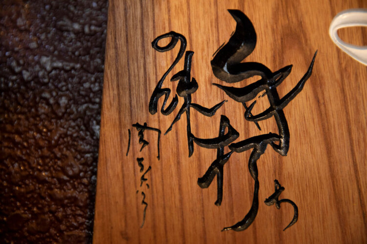店の看板に彫り込まれた「手打ちの味」の文字。