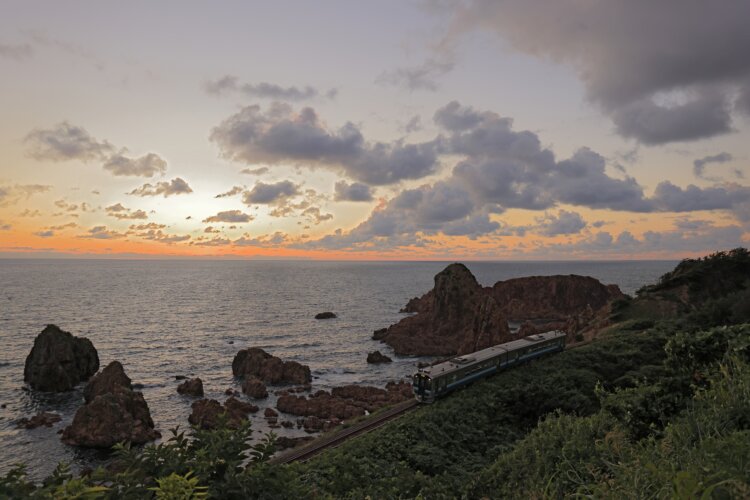 夕暮れに染まる日本海を走る五能線（写真＝レイルマンフォトオフィス）。