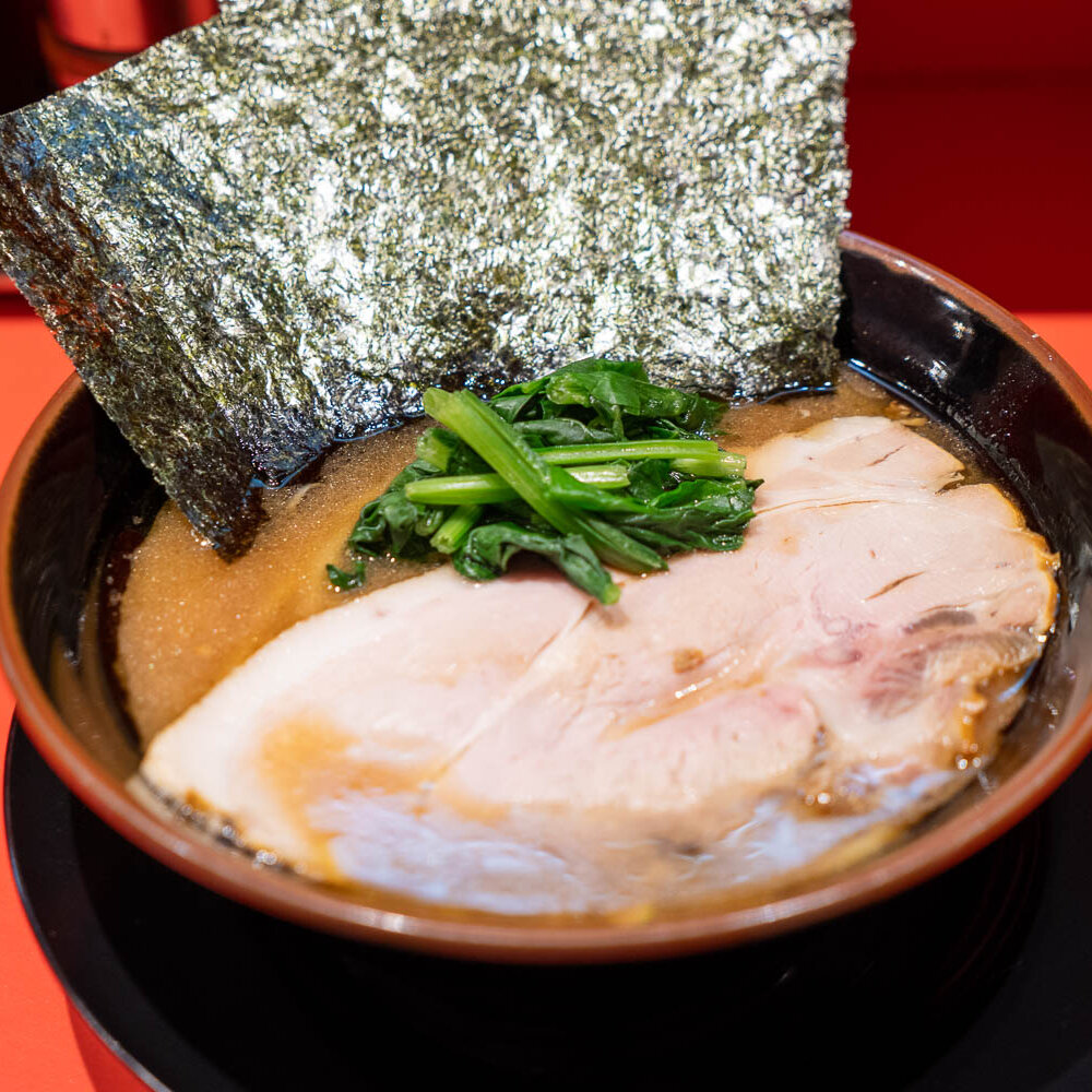 家系激戦区・蒲田の新鋭『ラーメン 三楽家』。赤いテント屋根の奥で、長年の友人同士で磨き上げたこだわりの一杯を