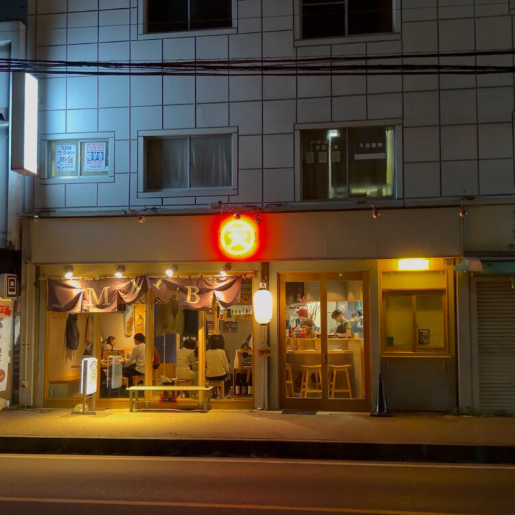 写真提供：『酒場食堂 マタタビ』　“天”のネオンサインが点る。ガラス張りで通りから店の様子がよく見える。