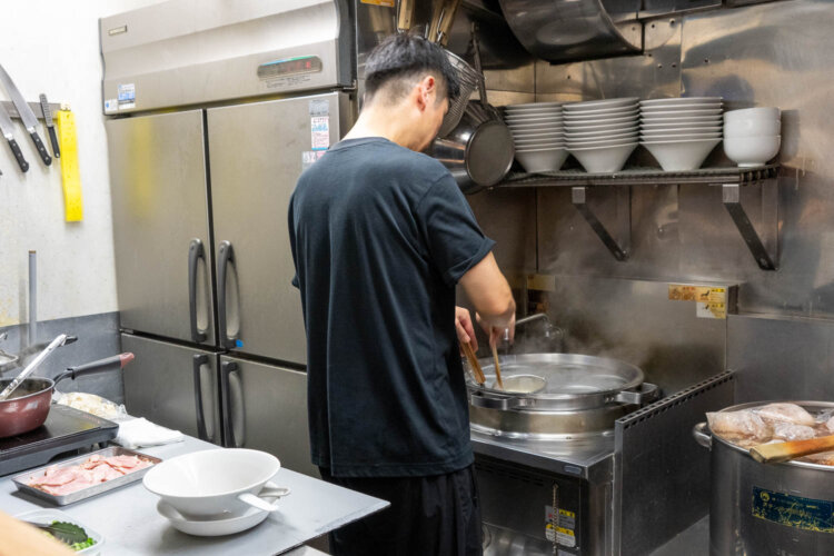 テボの中の麺をしっかりかき混ぜてゆでる店長の朴永俊さん。