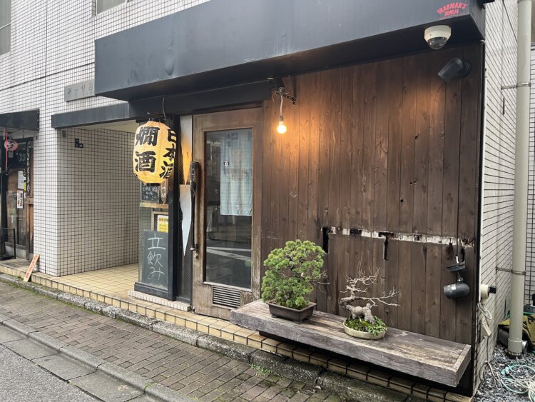 店先に「燗酒」の提灯（ちょうちん）が点る。黒いバットの取っ手を引いて中に入った。