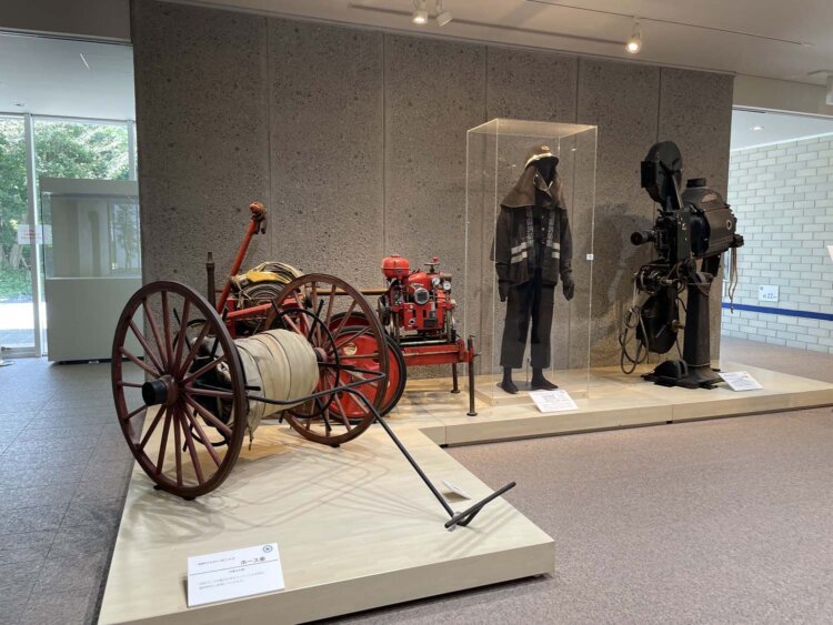 ホース車（左手前）、消防ポンプ車（左奥）、消防団団服（中央）。